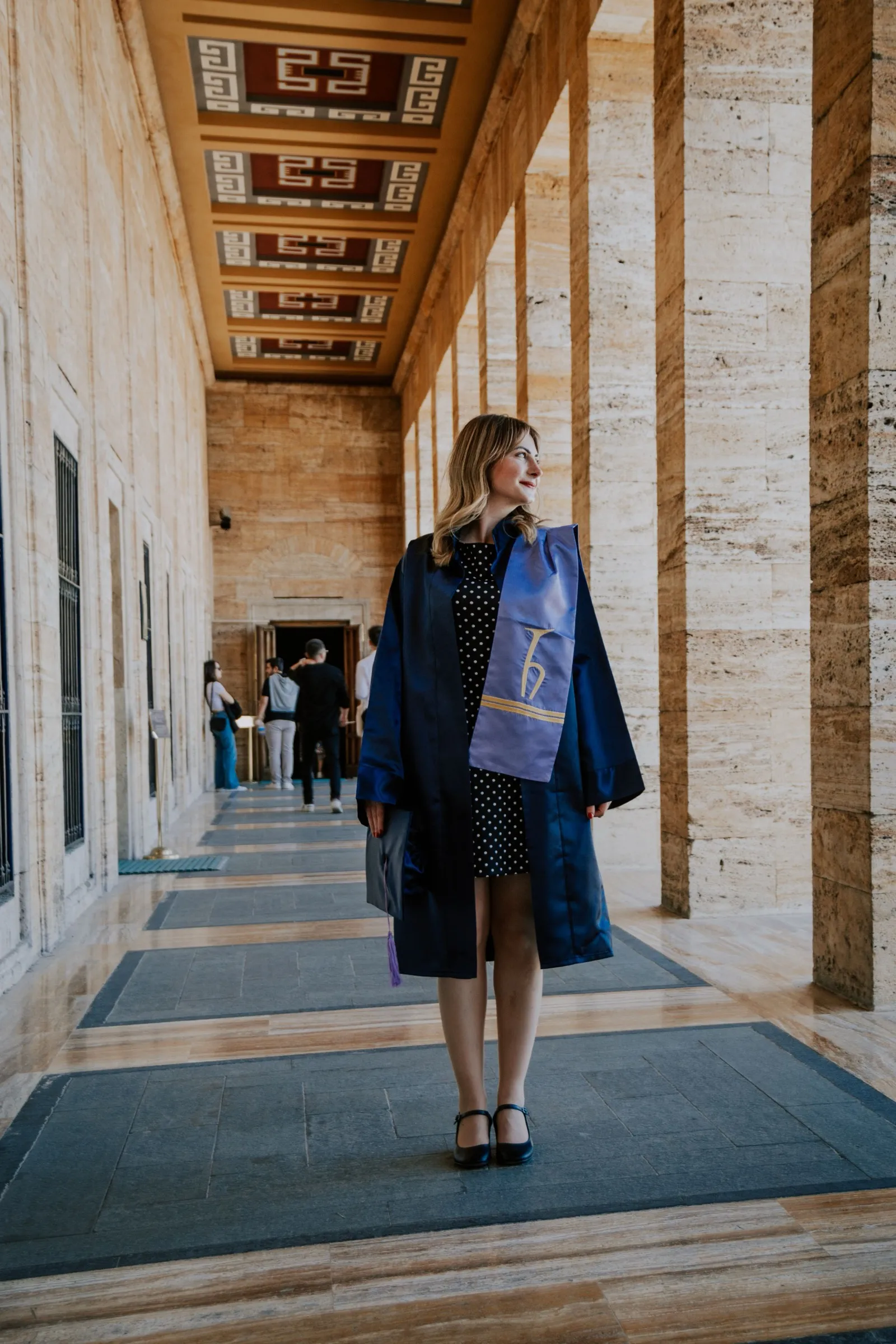 A student walking through a stone colonnade of a university building